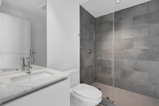 bathroom with vanity, toilet, and tiled shower