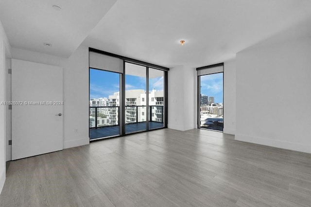 unfurnished room with a wall of windows and light wood-type flooring