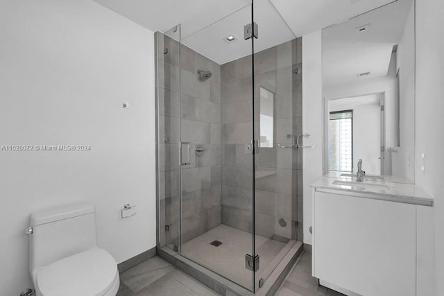 bathroom featuring tile flooring, a shower with shower door, vanity with extensive cabinet space, and toilet