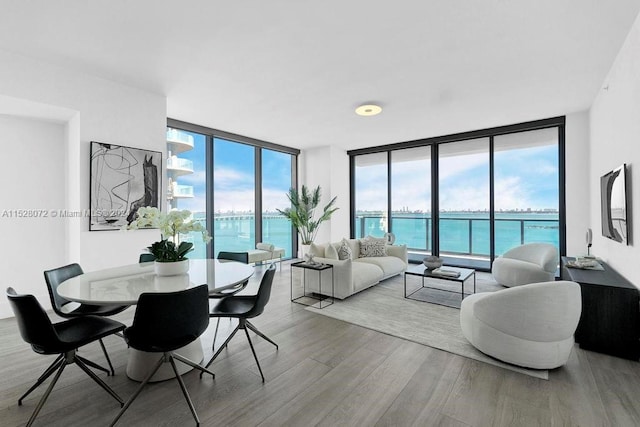 living room with floor to ceiling windows, light hardwood / wood-style floors, and a water view