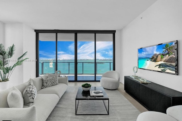 living room with a water view, floor to ceiling windows, and light hardwood / wood-style flooring