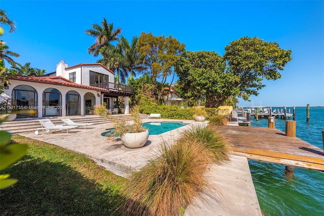 view of swimming pool with a water view, a dock, and a patio