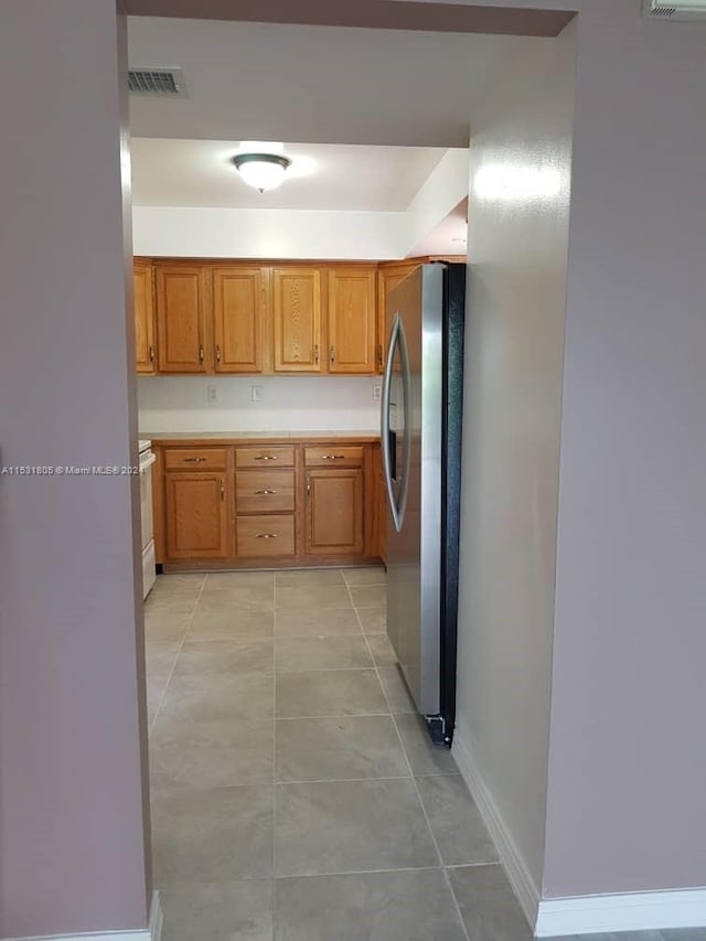 kitchen with stainless steel fridge, light tile flooring, and white range