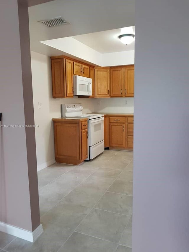 kitchen with white appliances and light tile flooring