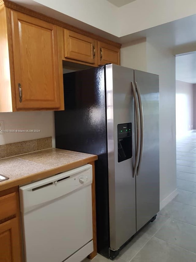 kitchen with light tile flooring, white dishwasher, and stainless steel fridge