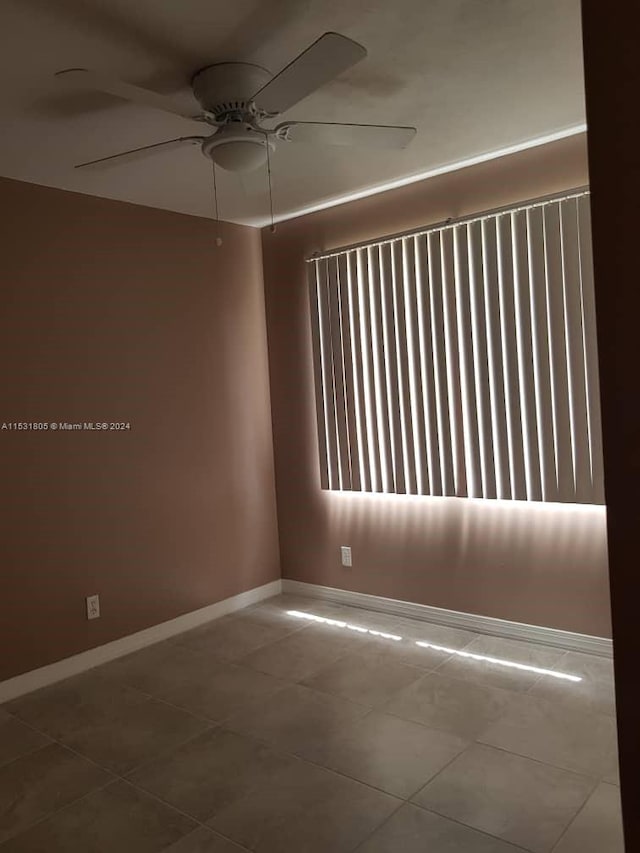 tiled empty room featuring ceiling fan