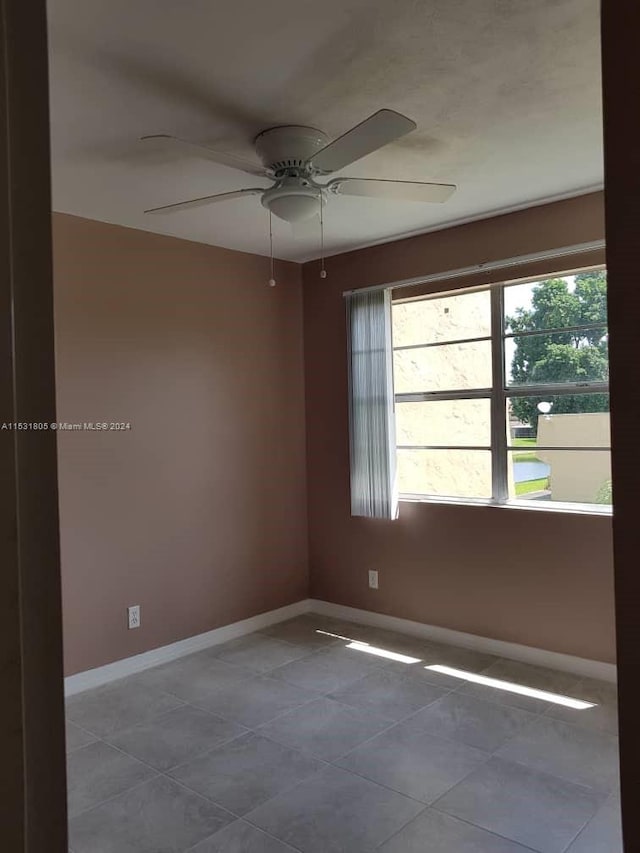 unfurnished room with dark tile floors and ceiling fan