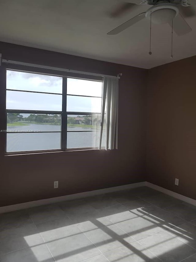 spare room with ceiling fan and light tile floors