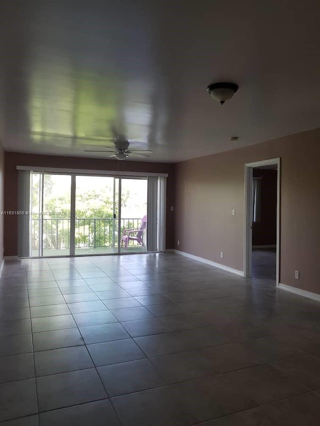 spare room with dark tile flooring, ceiling fan, and a healthy amount of sunlight