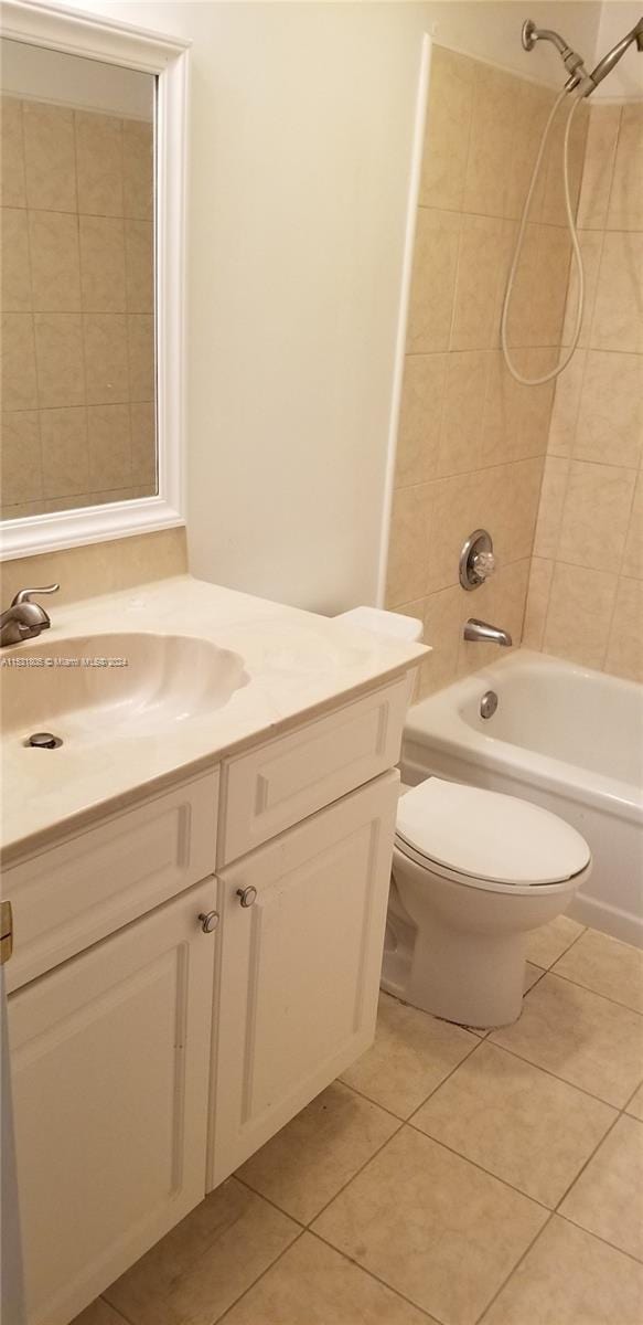 full bathroom with toilet, vanity with extensive cabinet space, tile floors, and tiled shower / bath combo