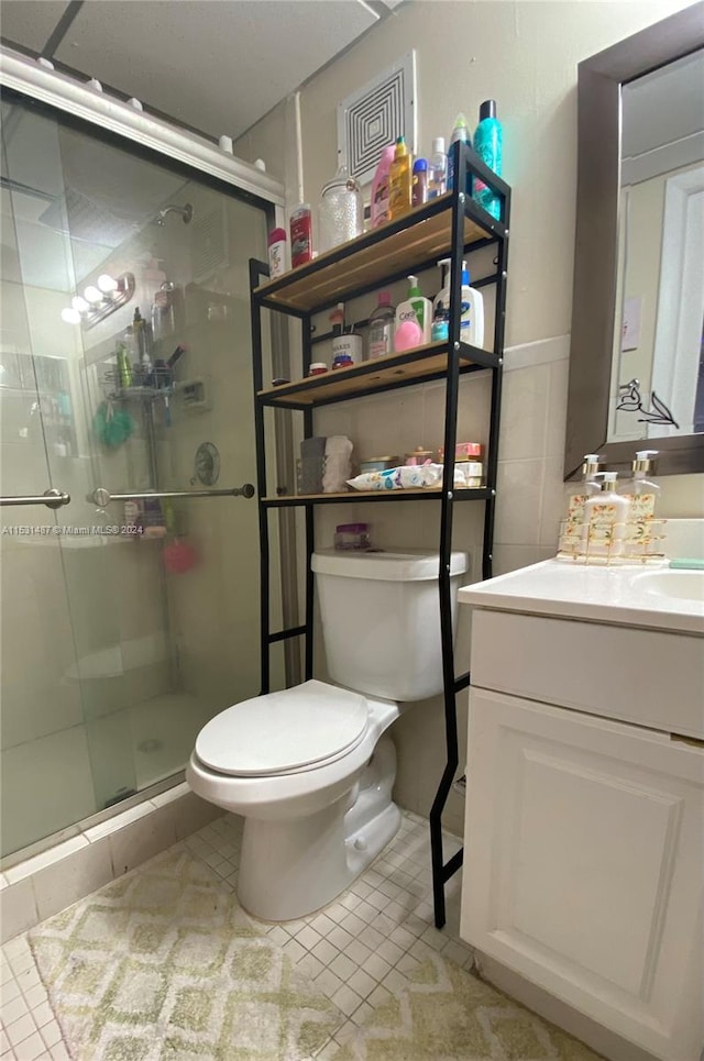 bathroom with walk in shower, toilet, tile floors, and vanity