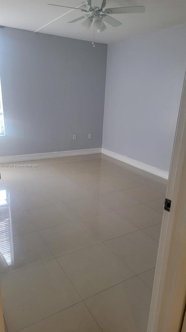 tiled spare room featuring ceiling fan