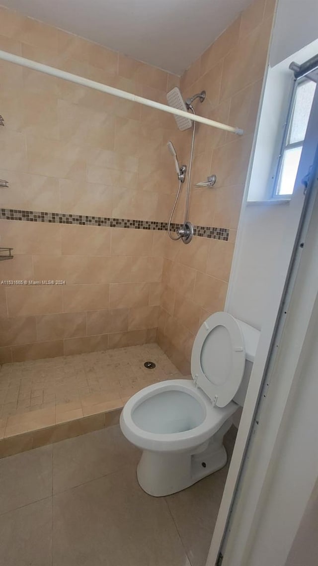 bathroom featuring tile flooring, tiled shower, and toilet