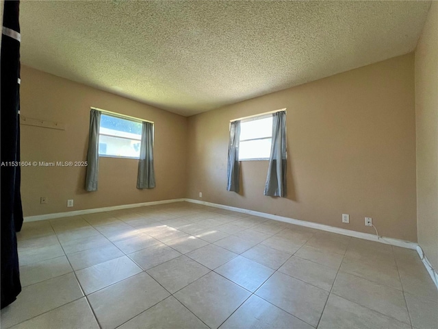 tiled empty room featuring a textured ceiling