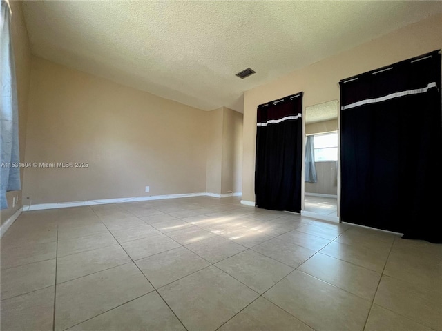 tiled empty room featuring a textured ceiling