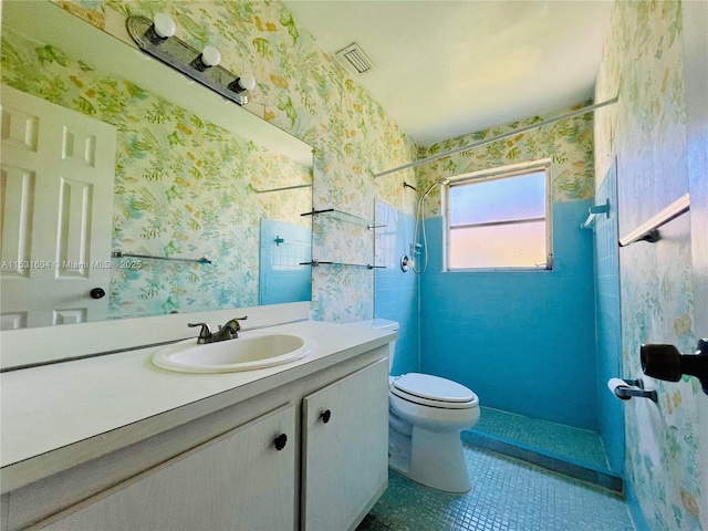 bathroom with tile patterned floors, vanity, toilet, and a shower