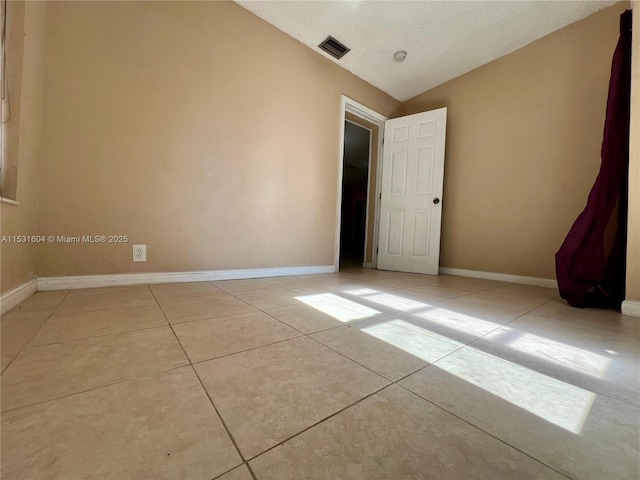 empty room featuring light tile patterned flooring and vaulted ceiling