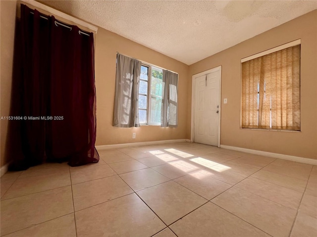 spare room with light tile patterned flooring and a textured ceiling