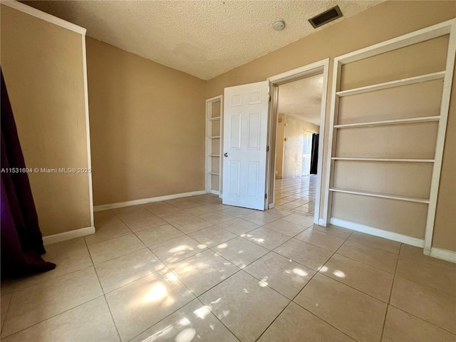 unfurnished bedroom featuring light tile patterned flooring and a textured ceiling