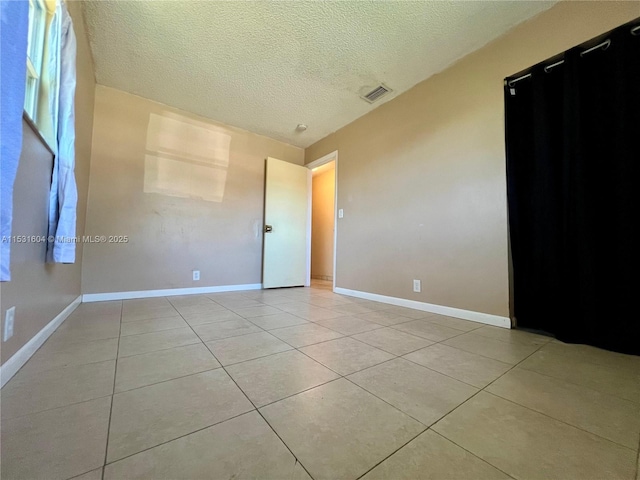 unfurnished room featuring light tile patterned floors and a textured ceiling