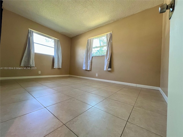 tiled empty room with plenty of natural light and a textured ceiling