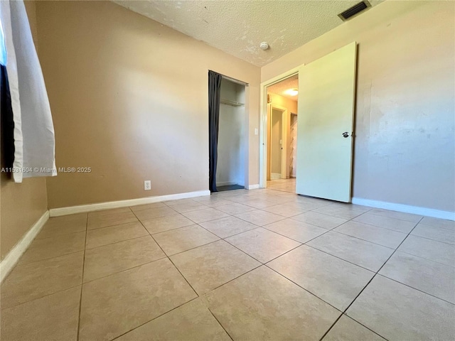 tiled spare room with a textured ceiling