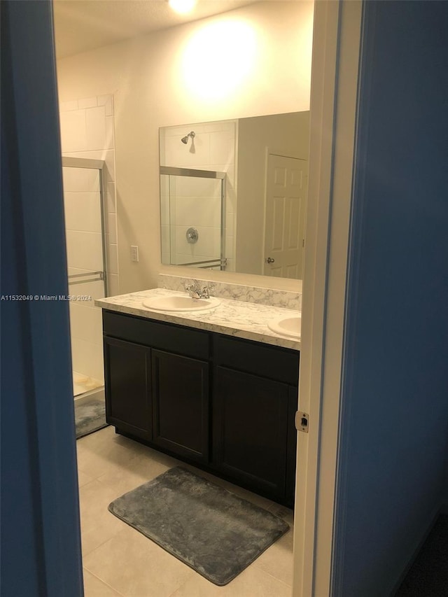 bathroom with tile floors, double vanity, and tiled shower