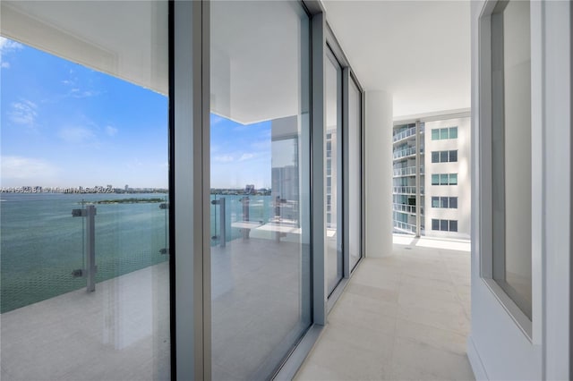 interior space with a water view, light tile flooring, and expansive windows