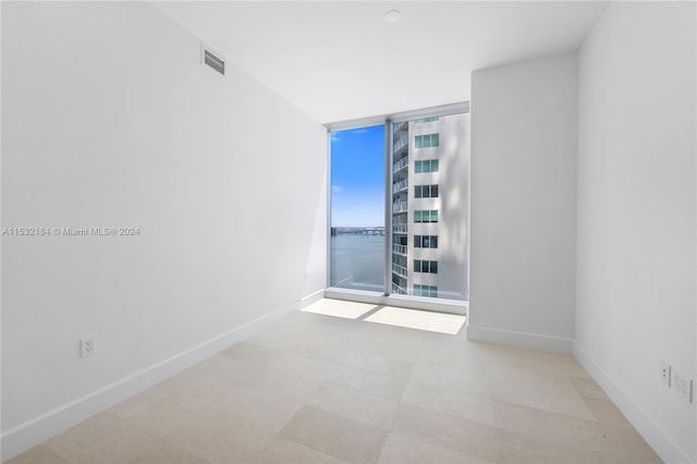 unfurnished room featuring light tile floors and a wall of windows