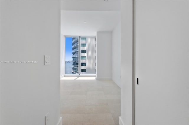 hall featuring floor to ceiling windows and light tile floors