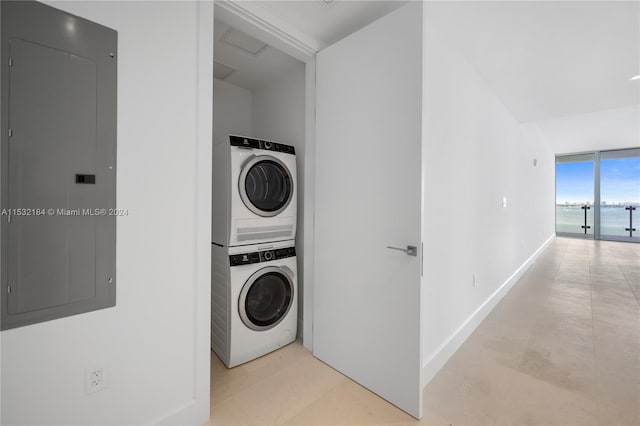 laundry room with a water view, stacked washer / drying machine, and light tile flooring