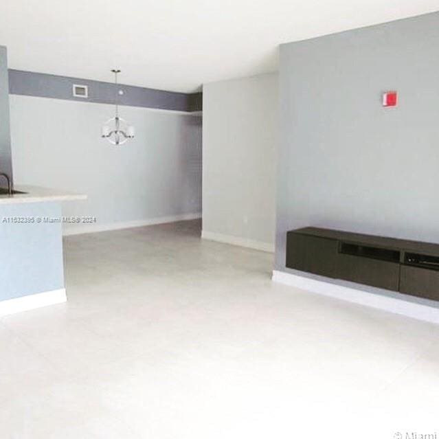 unfurnished living room featuring sink and a notable chandelier