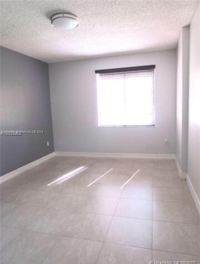 spare room featuring tile flooring and a textured ceiling