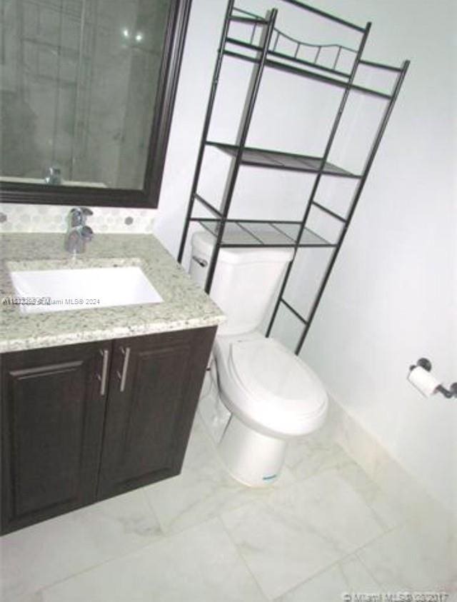 bathroom with vanity with extensive cabinet space, toilet, and tile flooring