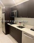 kitchen featuring stainless steel refrigerator, sink, and dark brown cabinetry