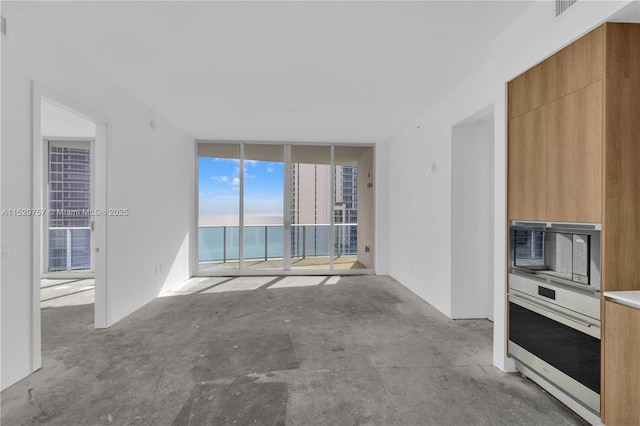 unfurnished living room with floor to ceiling windows and a water view