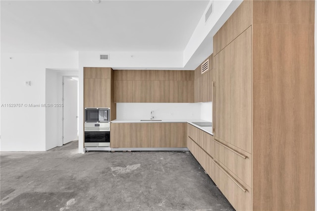 kitchen featuring light brown cabinetry, sink, and black appliances