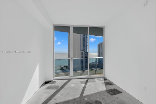 unfurnished room featuring a water view and a wall of windows