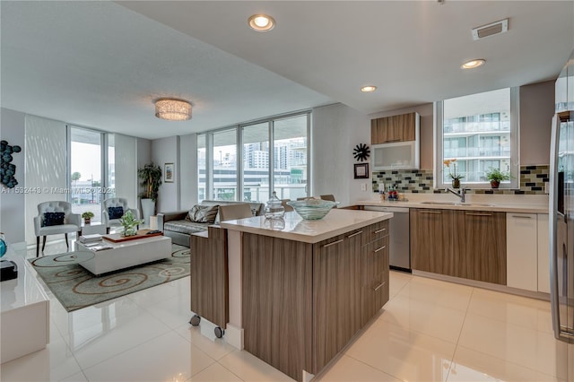 kitchen with light tile floors, floor to ceiling windows, backsplash, and dishwasher