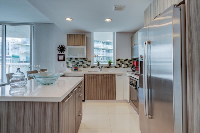 kitchen with sink, tasteful backsplash, light tile flooring, and stainless steel appliances