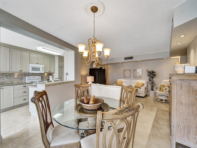 tiled dining area featuring a chandelier and a textured ceiling