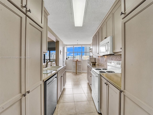 kitchen with backsplash, white appliances, sink, light tile floors, and a textured ceiling