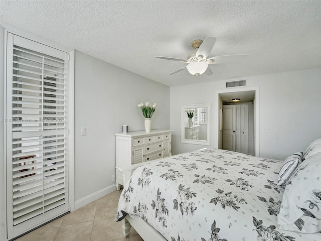 bedroom featuring light tile floors, ceiling fan, and a textured ceiling