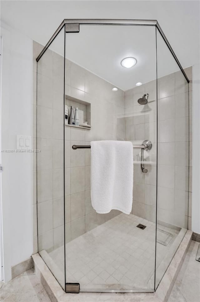 bathroom with an enclosed shower and tile flooring