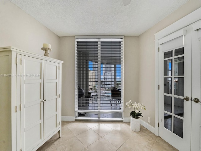 doorway with a textured ceiling, light tile floors, and french doors