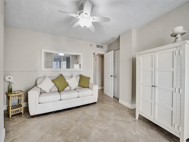 living room featuring a textured ceiling, ceiling fan, and light tile floors