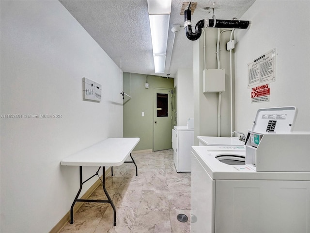 washroom featuring a textured ceiling, washer and clothes dryer, light tile flooring, and water heater