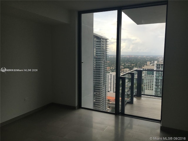 spare room featuring floor to ceiling windows and dark tile floors