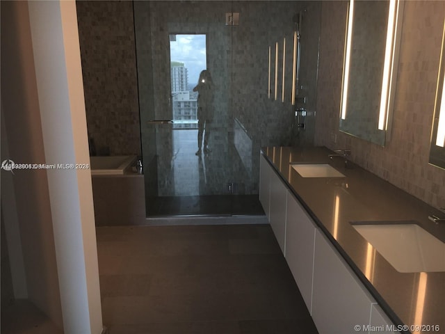 bathroom featuring vanity with extensive cabinet space, a shower with shower door, backsplash, dual sinks, and tile flooring