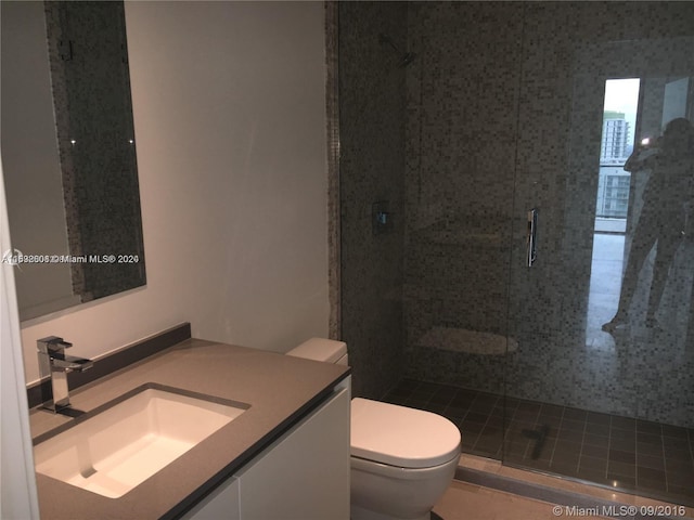 bathroom with vanity, a shower with door, and toilet